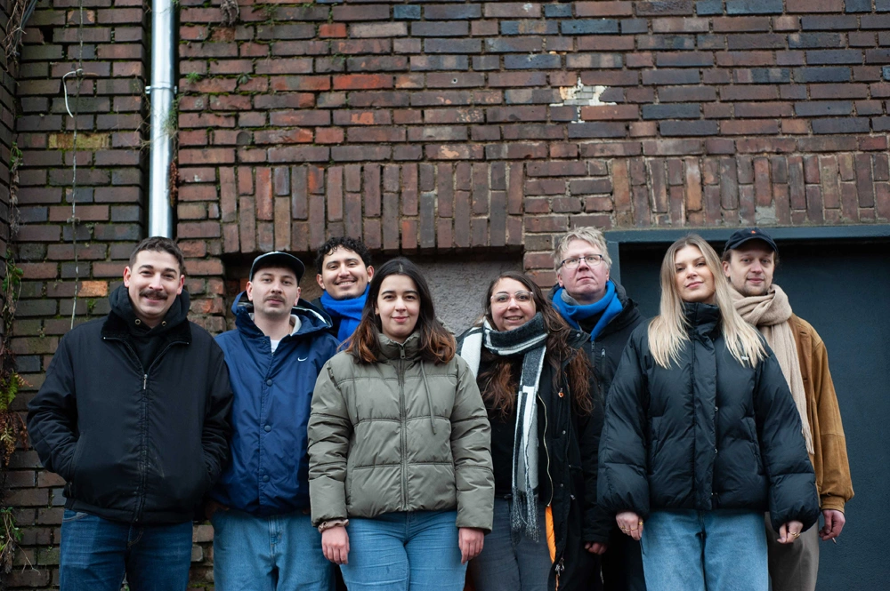 DJ at booth in a dark setting with vibrant neon/laser lighting